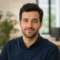 Professional author portrait in smart casual attire with a neutral office background.